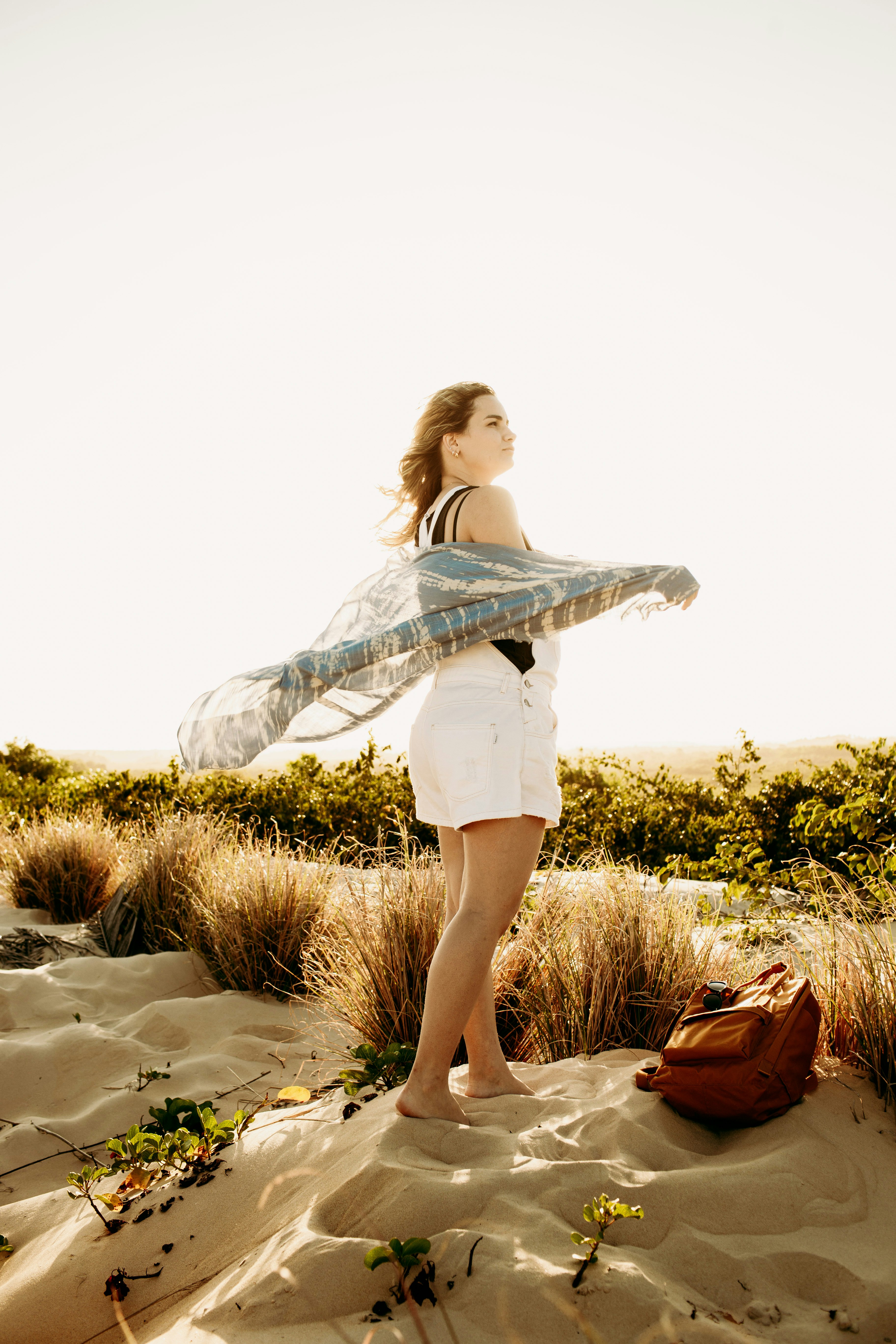 woman in white long sleeve shirt and white skirt standing on sand during daytime